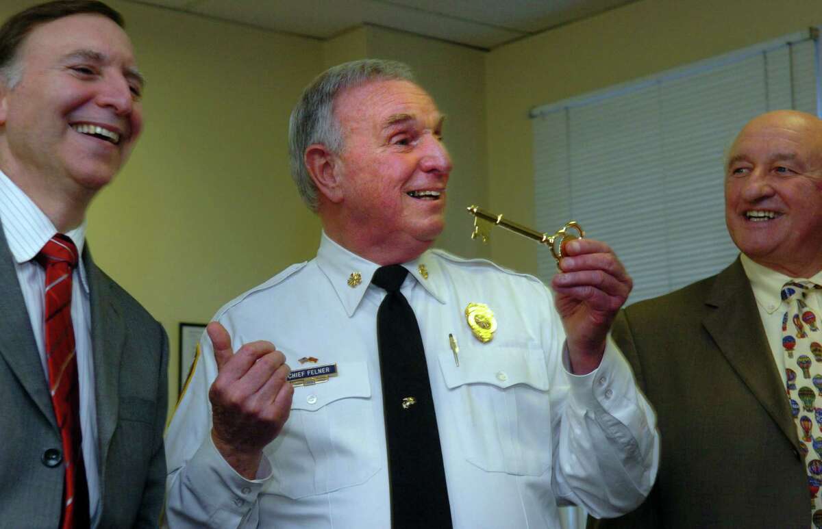 Fire Chief Richard Felner, holding a key to the city, gestures to Ken Flatto, First Selectman of the Town of Fairfield, as Dick Popilowski, right, looks on during a presentation honoring Felner's 50 years of service Wednesday February 4, 2009 at Independence Hall in Fairfield, Conn.