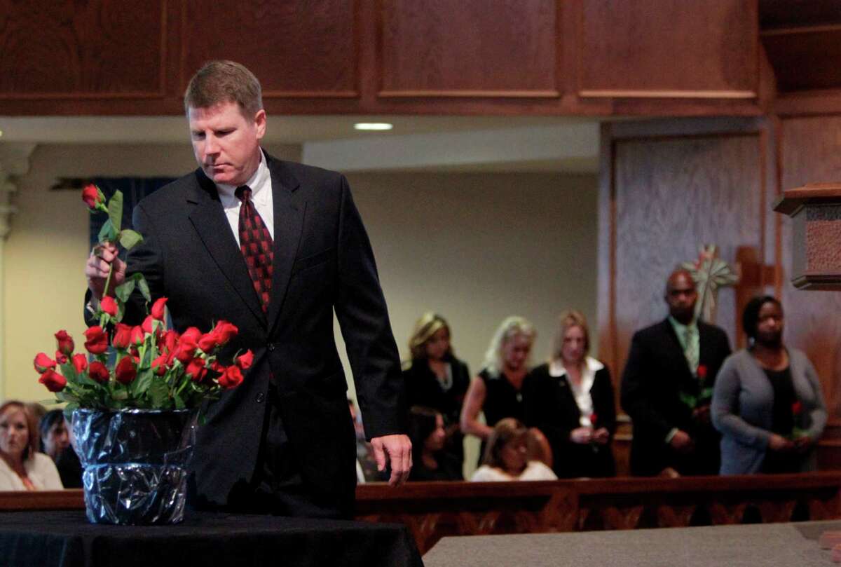 Special Agent Bobby Martin places a rose for his friend Special Agent Jerry Dove in the Roll Call of Martyrs during the FBI Law Enforcement Memorial Service at Our Savior Lutheran Church on Tuesday, May 15, 2012, in Houston. Special Agent Jerry Dove was killed in southwest Miami, Florida, during a gun battle with robbery suspects on April 11, 1986.
