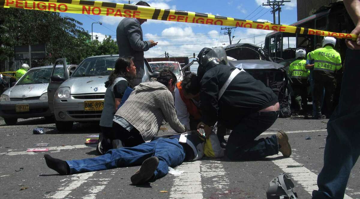 Pedestrians assist a man who was wounded when a bomb exploded in Bogota, Colombia, Tuesday, May 15, 2012. Colombian President Juan Manuel Santos says two people were killed in the bomb attack.