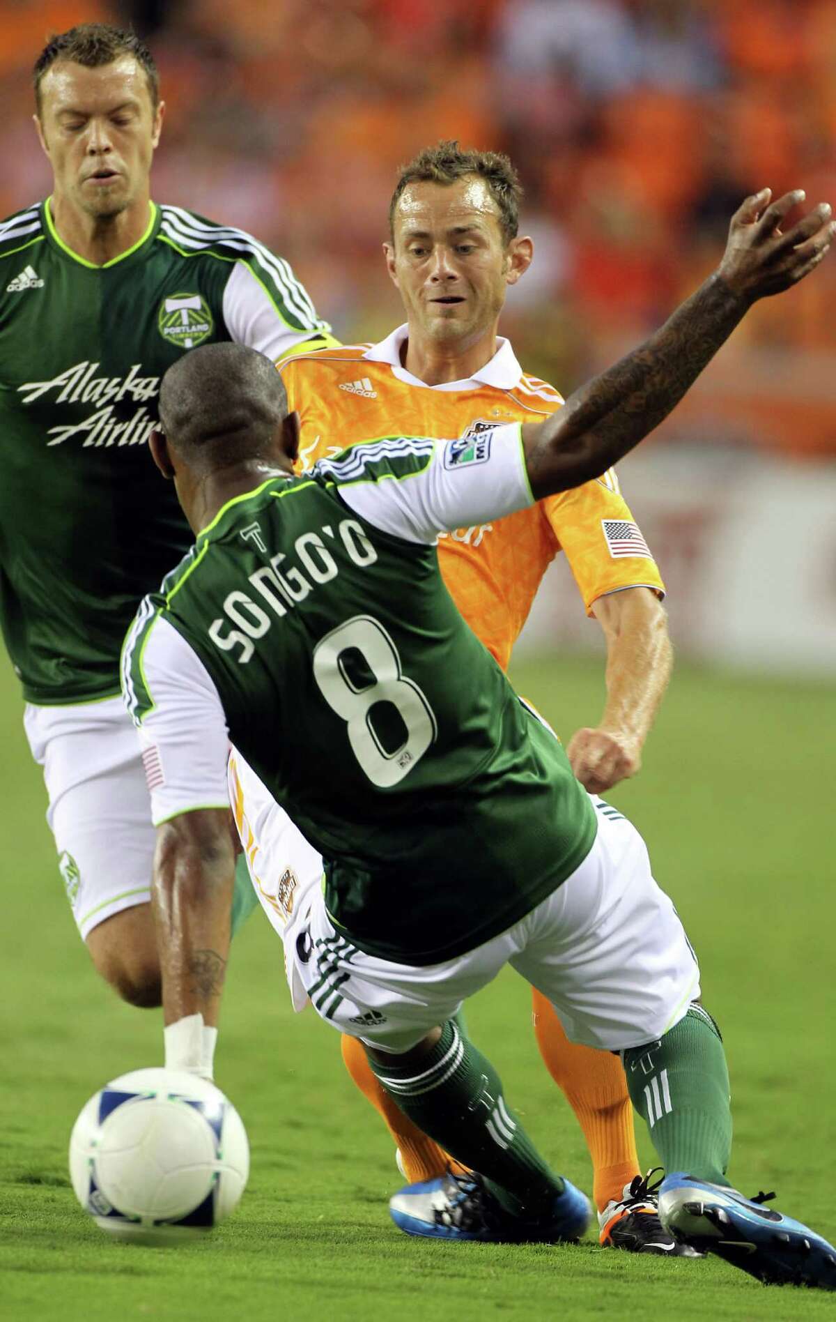 Dynamo midfielder Brad Davis looks to advance the ball past Portland Timber midfielder Franck Songo'o.
