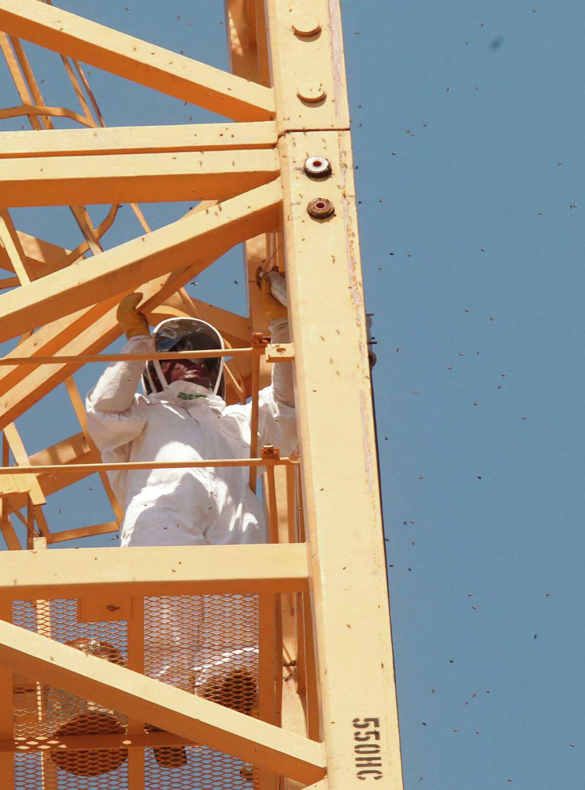 A Gotcha Pest Control technician treats the area where bees were found making a home inside the pipes of a crane at a high rise construction site along 5300 block of Brownway St. in the Galleria area on Wednesday, May 16, 2012, in Houston.