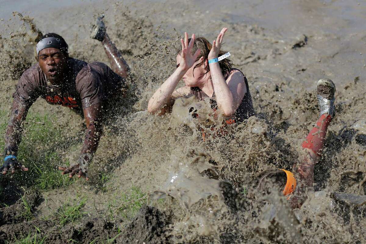 Balls Deep team members Raymond Henderson, left, Alison Schwalenberg and Kelsey Oakley unsuccessfully dive for the ball during a match in the mud volleyball tournament, Saturday, May 19, during the 2012 Strawberry Festival at the Pasadena Fairgrounds in Pasadena.