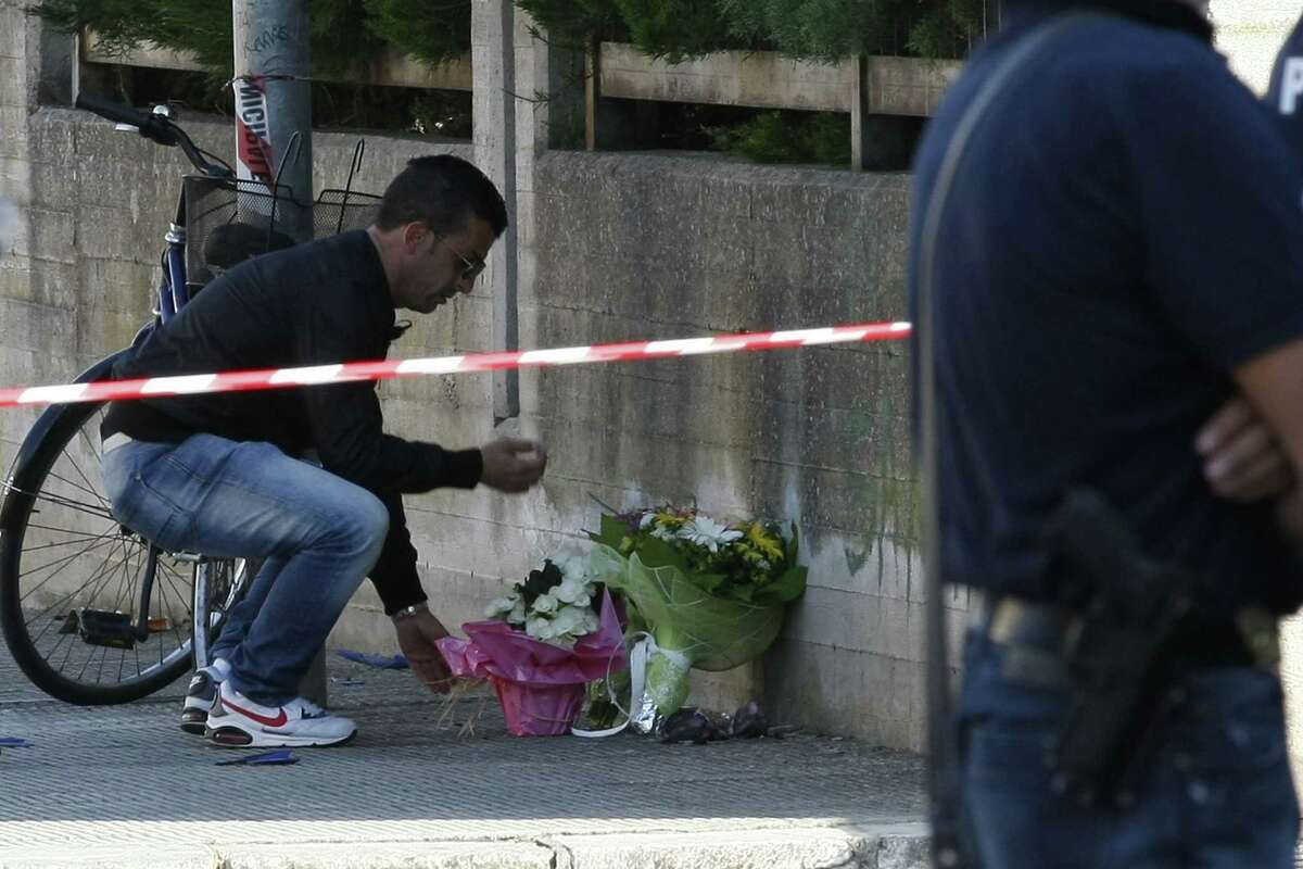 A man places flowers on the site of a blast near a school in Brindisi on May 19, 2012.