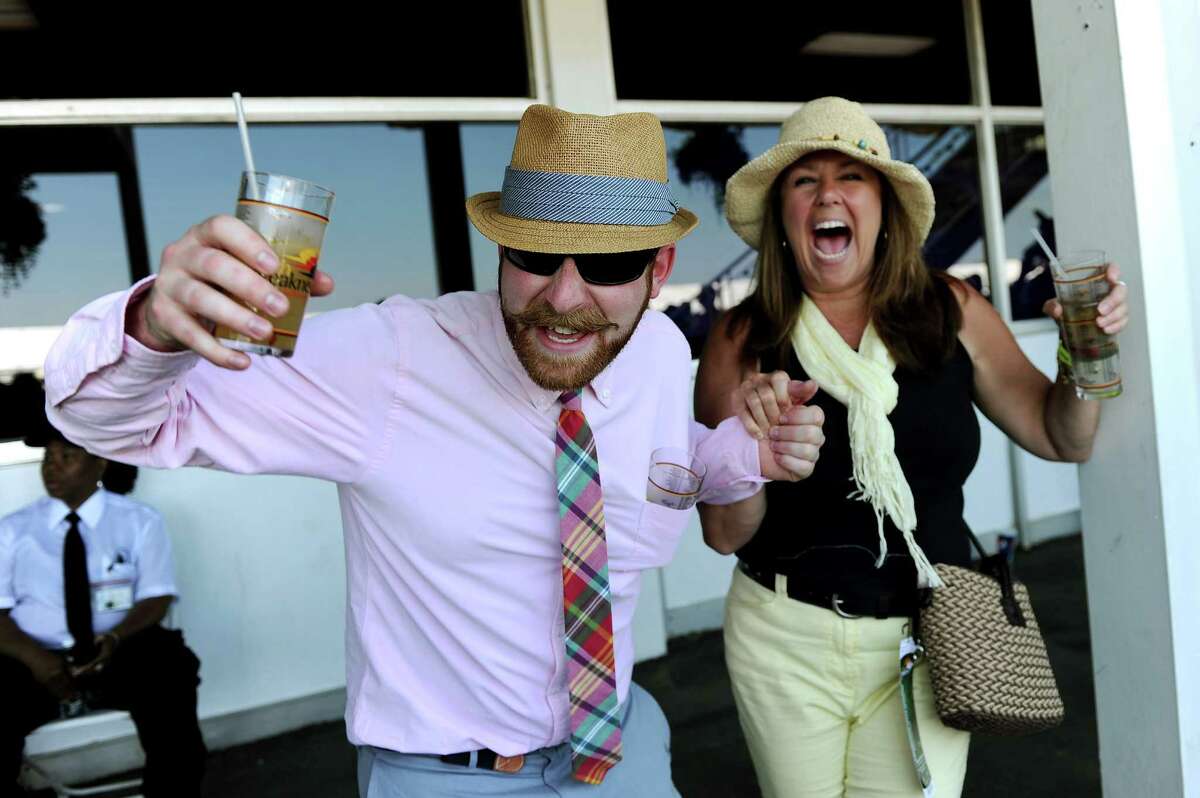 Joshua Rathbone and Monica McDowell of West Chester, Pennsylvania, cheer for a race prior to the 137th running of the Preakness Stakes at Pimlico Race Course on May 19, 2012 in Baltimore, Maryland.