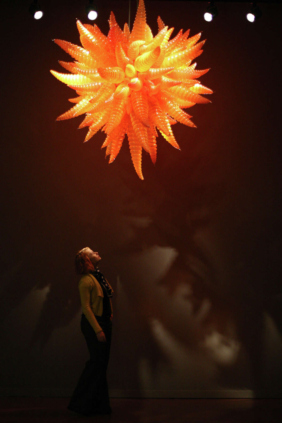 Visitor Jynn Hintz-Romano looks up at an installation in the "Chandeliers Room" during the grand opening of the Dale Chihuly Garden and Glass museum at the Seattle Center on Monday, May 21, 2012.