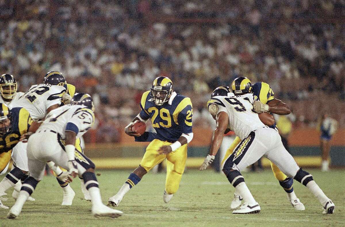 Los Angeles Ram running back Eric Dickerson, center, cuts through a wide hole in the San Francisco defense, including Thomas Benson (57, left) and Leslie O?Neal (91, right) for a 15-yard gain in the second quarter of NFL preseason game at Anaheim Stadium, Saturday, August 23, 1986, Anaheim, Calif. Earlier in the quarter Dickerson had run 74 yards for a touchdown. (AP Photo/Lennox McLendon)