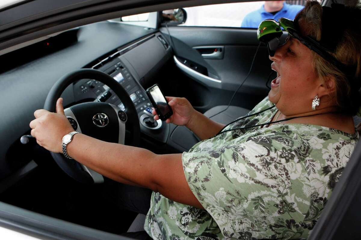Esther Reyes reacts while attempting to send a text and drive at the AT&T driving simulator outside City Hall Wednesday, May 23, 2012, in Houston. "I crashed," she said. The simulator helped kick off the reminder of the Memorial Day weekend being some of the deadliest on the road for teen drivers. The 30-city tour of the simulator is to make people aware of the dangers of texting and driving.