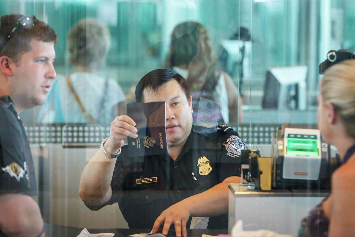 U.S. Customs and Border Protection officer Nguyen looks at a passport at the Federal Inspection Services customs facility at Bush Intercontinental Airport in Terminals E. With Hobby Airport looking to become an international airport, would that make customs wait times longer at both airports or would more customs officers be added to the area?
