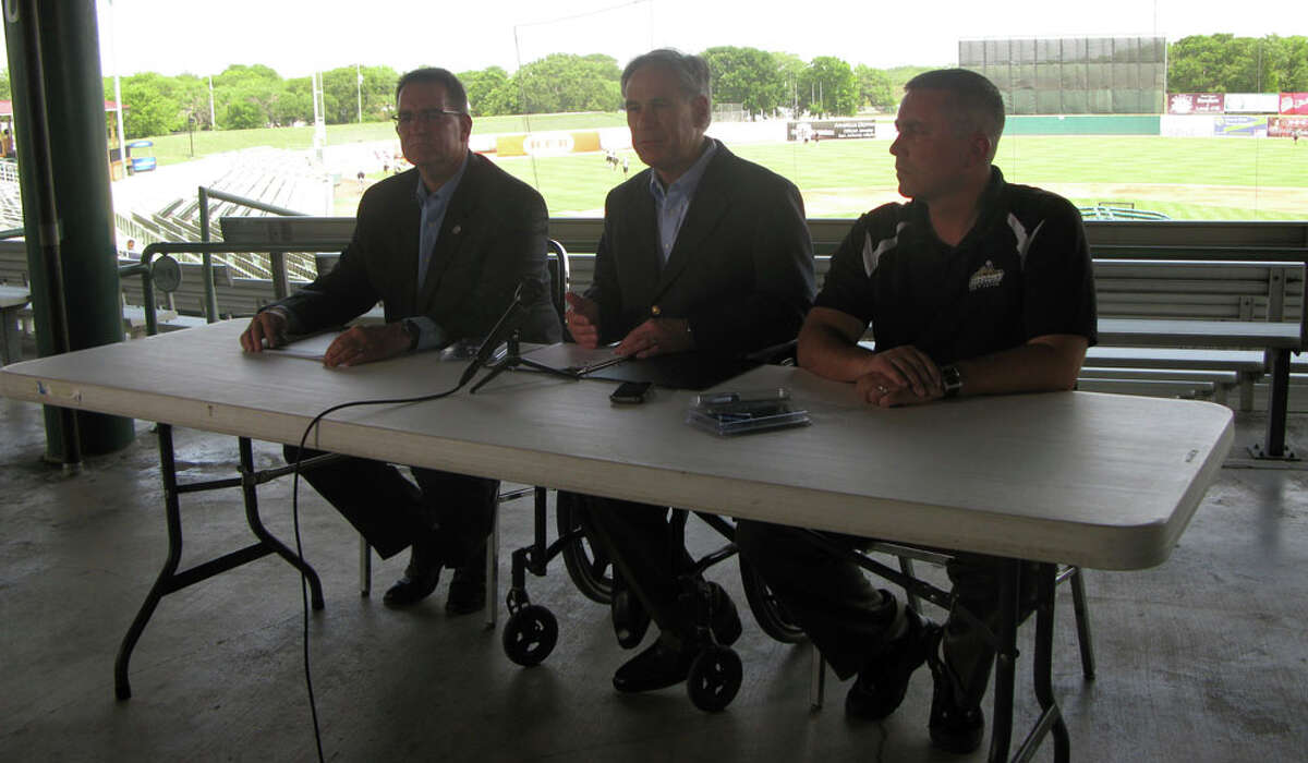 Attorney General Greg Abbott addresses media hours before his office donated child protection flash drives to the first 1,000 fans at a Missions baseball game Friday night. He is flanked by David Boatright (at left), executive director of the Texas office of the National Center for Missing & Exploited children (right), and San Antonio Missions General Manager David Gasaway.