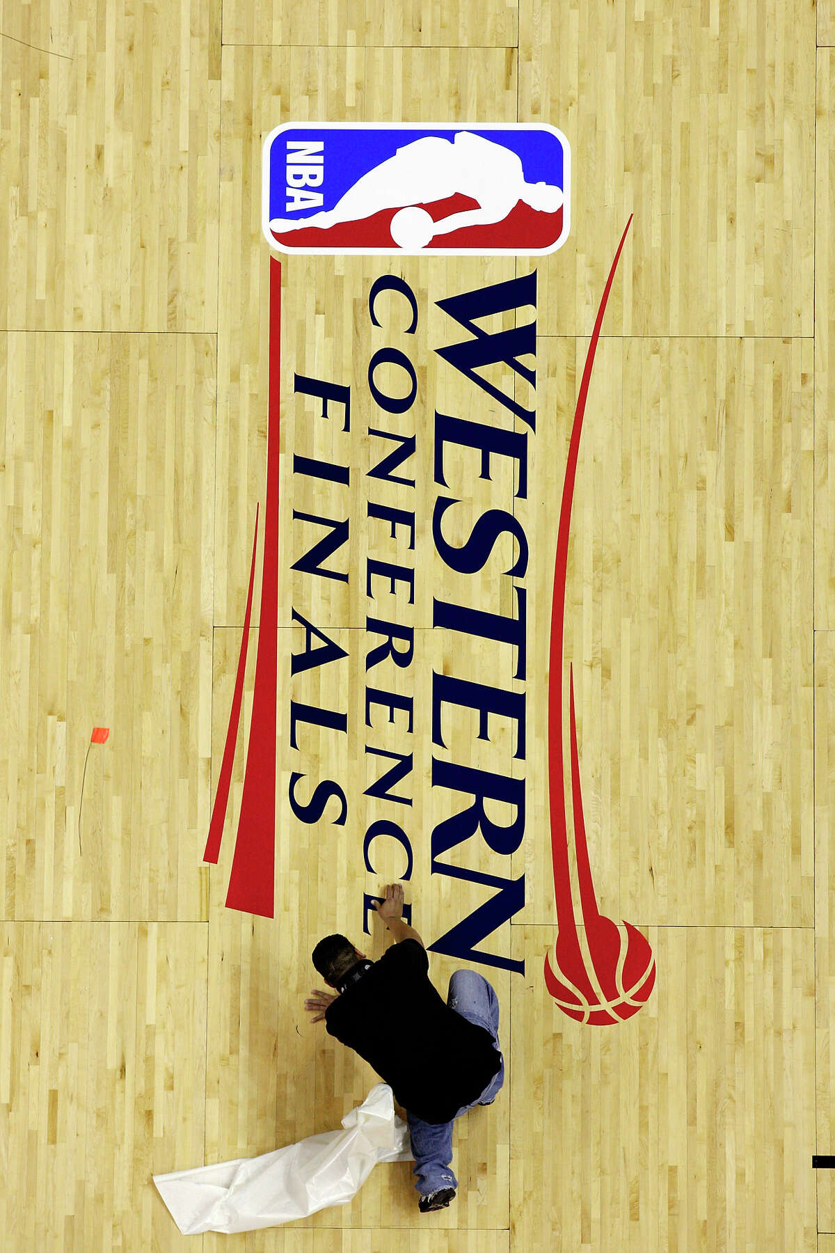 AT&T Center employee Cecilio Santibanez applies the Western Conference Finals logo to the court Friday May 25, 2012 at the AT&T Center.