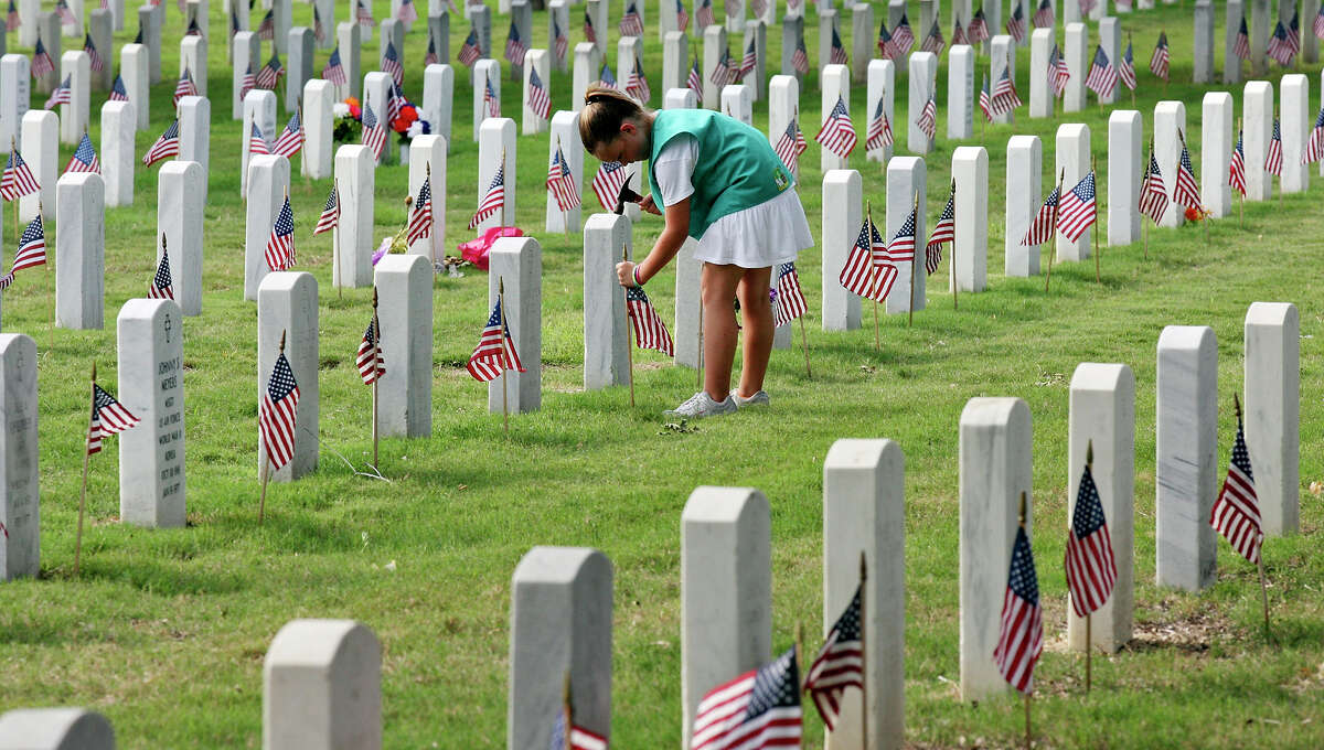 Girl Scout Taylor Thorpe, 9, places an American flag on a grave for Memorial Day at Fort Sam Houston National Cemetery for Friday May 25, 2012. The local Memorial Day Program is held annually held to remember and honor all military members who have served or are currently serving in the military. The event is scheduled for 9:30 a.m. at the new assembly area located on the east side of Ft. Sam Houston National Cemetery. Larry Romo, director of the Selective Service System and who is from San Antonio, will give the keynote address.