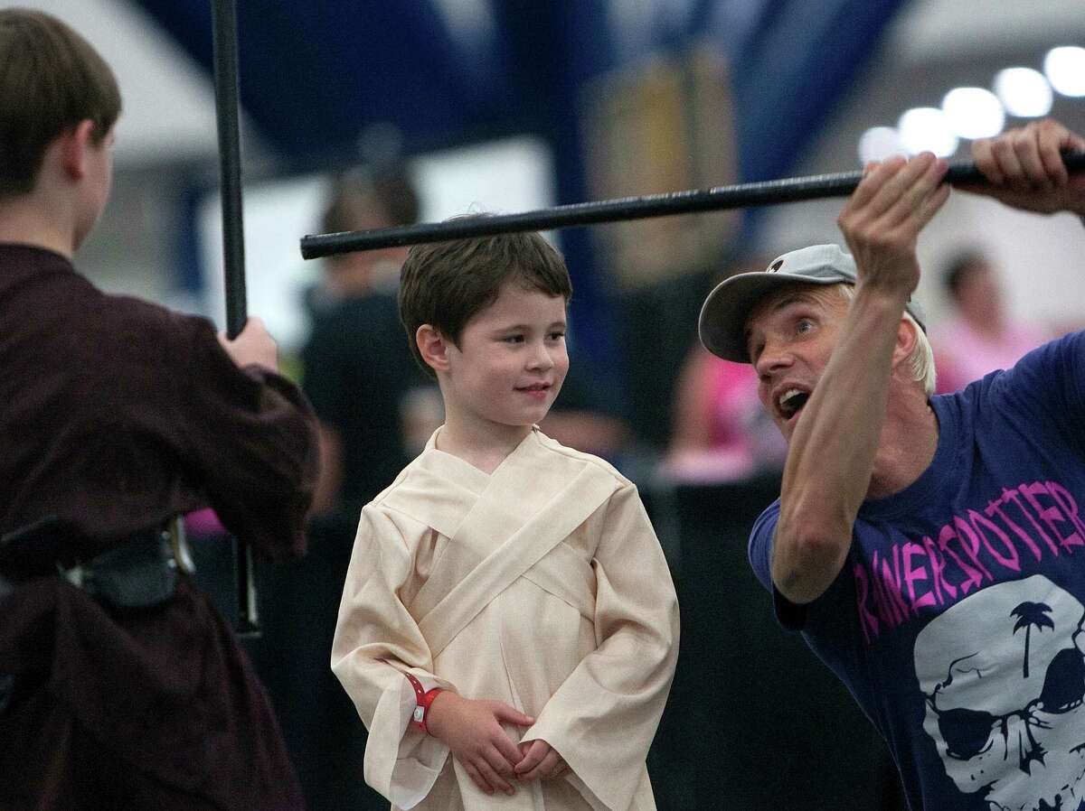 Evan McCoy, 6, left, and Austin McCoy, 4, center, listen as they take Jedi lessons from Nick Gillard, right, at Comicpalooza at the George R. Brown Convention Center Saturday, May 26, 2012, in Houston. Comicapalooza is a multi-format pop culture convention in the southwest region of the United States drawing fans of comics, science fiction, fantasy, video and table-top gaming, anime, music and film.