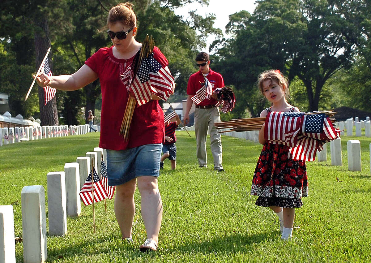 Catherine Gerdes, left, wife of U.S. Marine Master Gunnery Sgt. Timothy Gerdes, who is stationed at Camp Leatherneck in Afghanistan, places United States flags on graves at Alexandria National Cemetery in Pineville, La., Saturday, May 26, 2012, in preparation for Monday's Memorial Day program. The Gerdes' children, Madeline, right, and her brothers Ethan, Colton and Natha help out. (AP Photo/The Daily Town Talk, Melinda Martinez) NO SALES