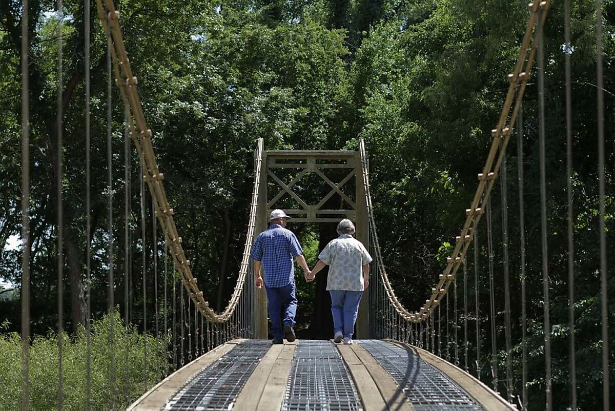 MULVANE, KS - MAY 21, 2012 Larry and Barbara Richardson have a replica Golden Gate Bridge on their property in Mulvane, KS. The suspension bridge was built by Larry, his brother and his father over a 7-8 year time span. The group started the project in 1994 and finished it up in August 2001. They poured all the concrete they needed by themselves with bags of concrete. Larry said he got the timbers for the bridge for free and the cables too. Larry bought a postcard of the Golden Gate Bridge while in California briefly while shipping out to Vietnam in 1968 while in the Army. That postcard he kept all those years and used it as the guide for how he would build his replica bridge. He did no engineering for the project he just looked at the picture and figured out how to make it work. His bridge crosses the small Cowskin Creek and he can now access a small section of his land that he wasn't able to before. Larry painted his bridge a gold color, unlike the original Golden Gate Bridge. He says he has to buy the paint from a local hardware store and they only sell it in pint containers. He has painted the bridge twice, every time with a 1 inch trim brush.