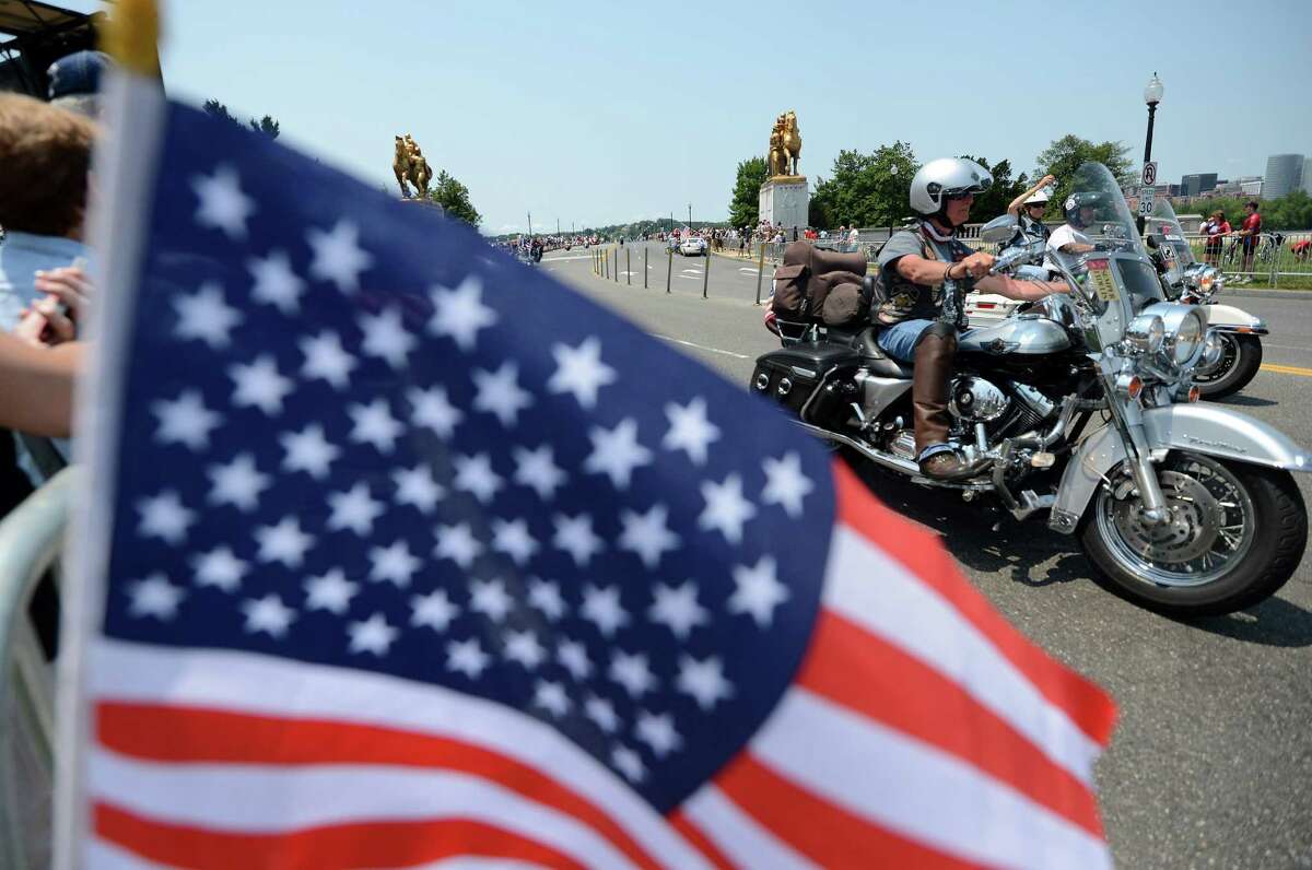People wave US flags as riders on their motorbikes roar past during the Rolling thunder demonstration in Washington, DC, on May 27, 2012. The 25th Annual Rolling Thunder rumbled into town to show support for veterans past and present, those who have fallen in war and those who are missing in action. It's expected nearly one million riders will be here through Memorial Day.