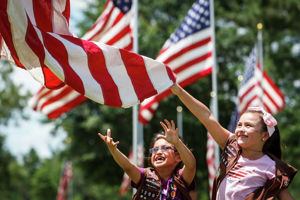 Lucia Duran, 7, left, and Anaka Womack, 8, right, keep an American Flag from touching the ground as they and other Girl Scouts raise a flag at the Houston VA National Cemetery, Sunday, May 27, 2012, in Houston. Over 229 flags were raised in honor of the upcoming Memorial Day Service.