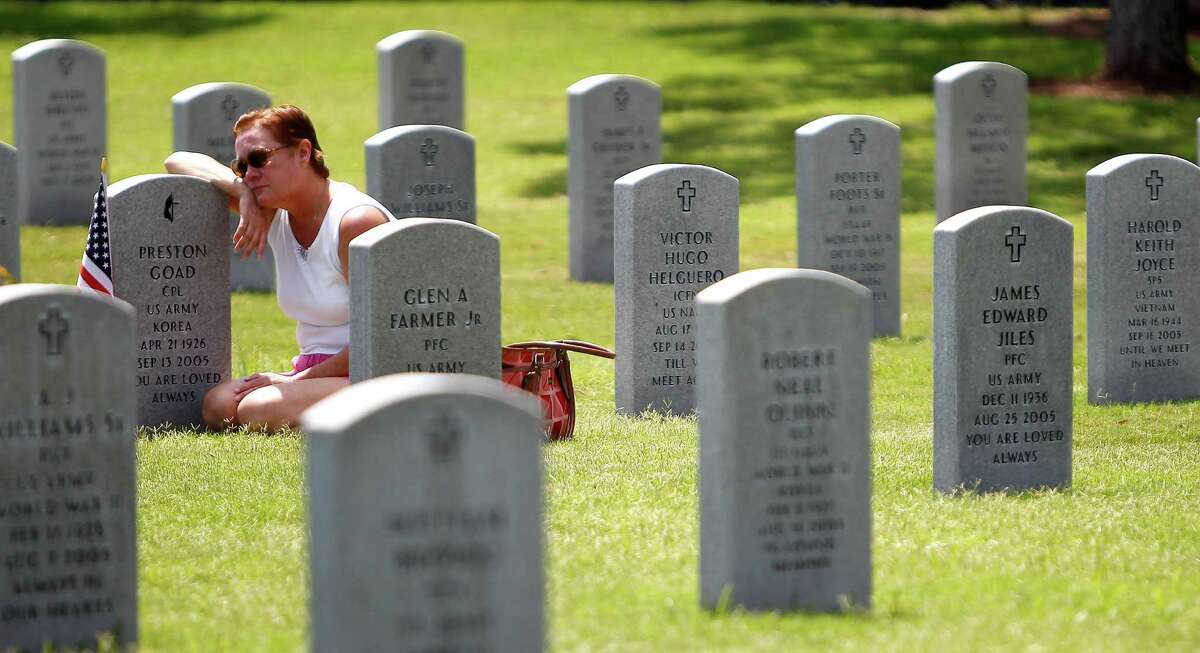 Debbie Hinojosa sits at the grave of her father, Preston Goad, an army veteran, who died in September 2005 on Memorial Day at the Houston National Cemetery, Monday, May 28, 2012, in Houston. "I miss my daddy..he was my angel" said Hinojosa.