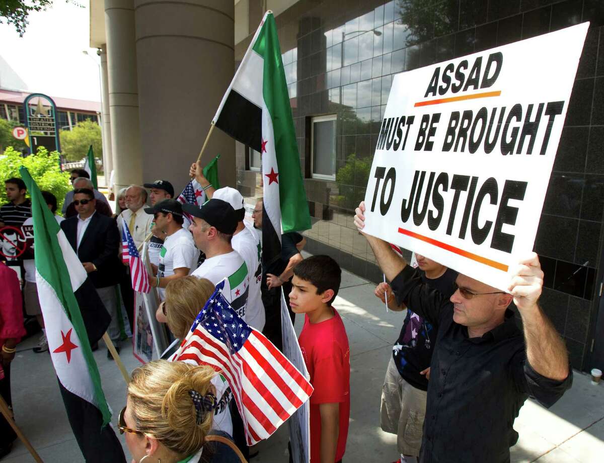 Demonstrators march outside the Bob Casey Federal Courthouse during a news conference condemning the Syrian government Tuesday, May 29, 2012, in Houston. Rep. Sheila Jackson Lee, D-Houston, and members of the local Syrian-American community spoke out against the violence in Syria. The latest round of violence in Syria took place over the weekend, where a reported 108 civilians were killed. ( Brett Coomer / Houston Chronicle ) .