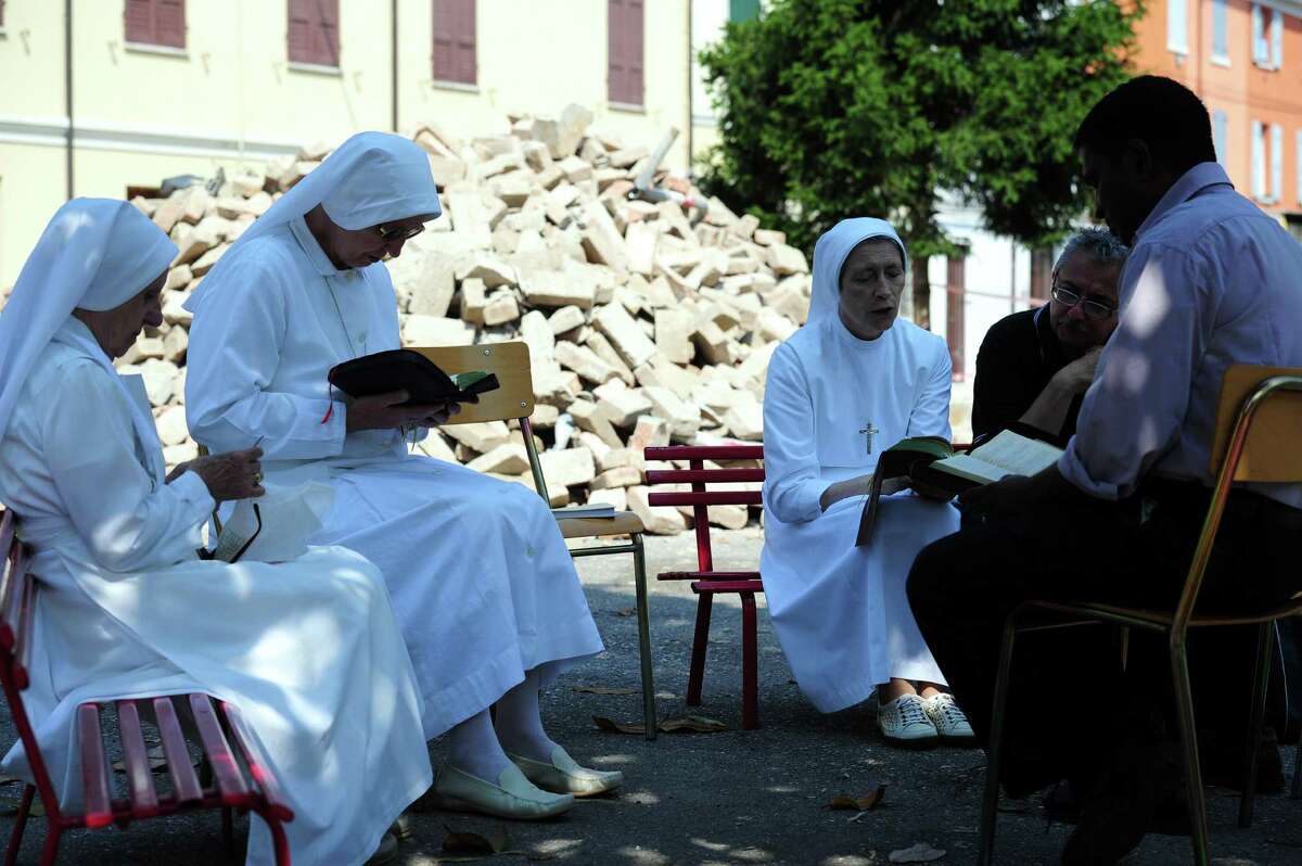 Nuns and priests pray near rubble after an earthquake Wednesday in Mirandola. Dozens of aftershocks hit northeastern Italy overnight as thousands of jittery survivors spent the night in tent camps after the region's second killer quake in days. (OLIVIER MORIN/AFP/GettyImages)
