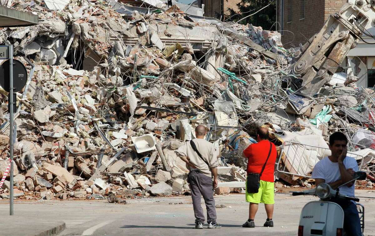 People stand in front of a collapsed building in Cavezzo, northern Italy, Wednesday. A magnitude 5.8 earthquake struck Tuesday that felled old buildings as well as new factories and warehouses in a swath of Italy north of Bologna. The quake, which followed a May 20 magnitude-6.0 quake in the same area, dealt another blow to one of the country's most productive regions at a time when Italy is struggling to restart its economy.