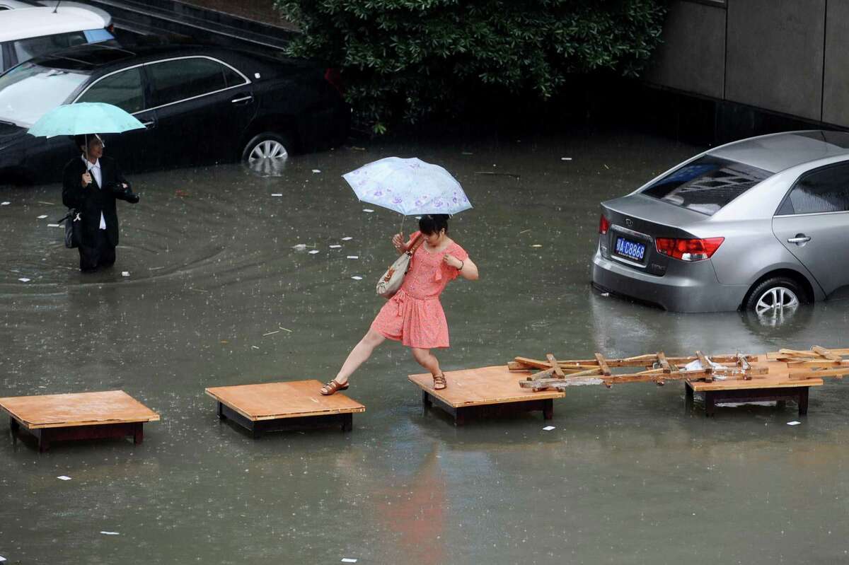 A woman crosses a flooded street on a row of tables in Wuhan, central China's Hubei province. China is hit by big summer rainfalls every year, as heavy downpours across large swathes of the country trigger flooding, landslides and other rain-related disasters.