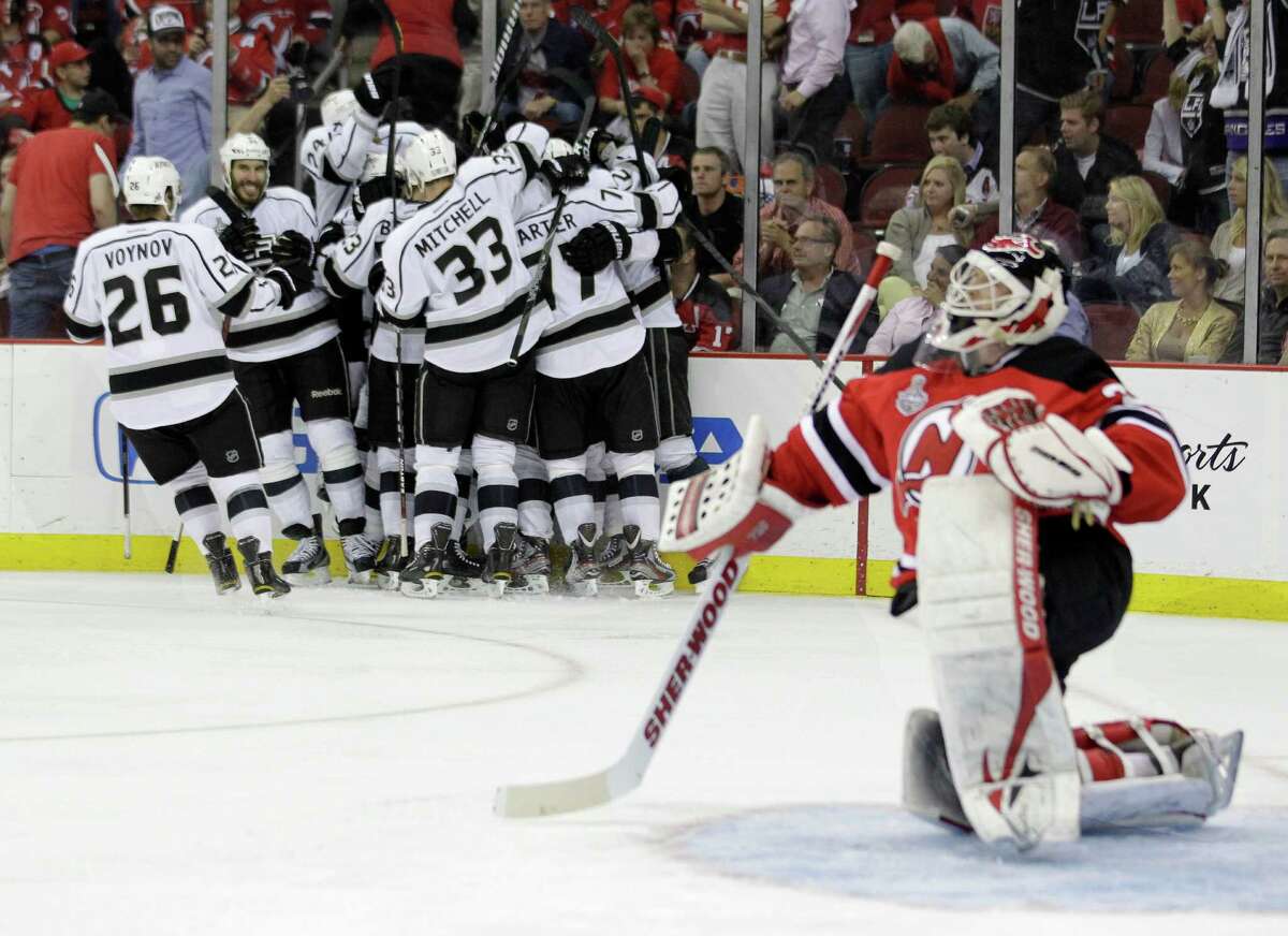 New Jersey Devils' goalie Martin Brodeur gets up from the ice after as the Los Angeles Kings celebrate their winning goal during the overtime period of Game 1 of the NHL hockey Stanley Cup finals Wednesday, May 30, 2012 in Newark, N.J. The Kings won the game 2-1. (AP Photo/Julio Cortez)