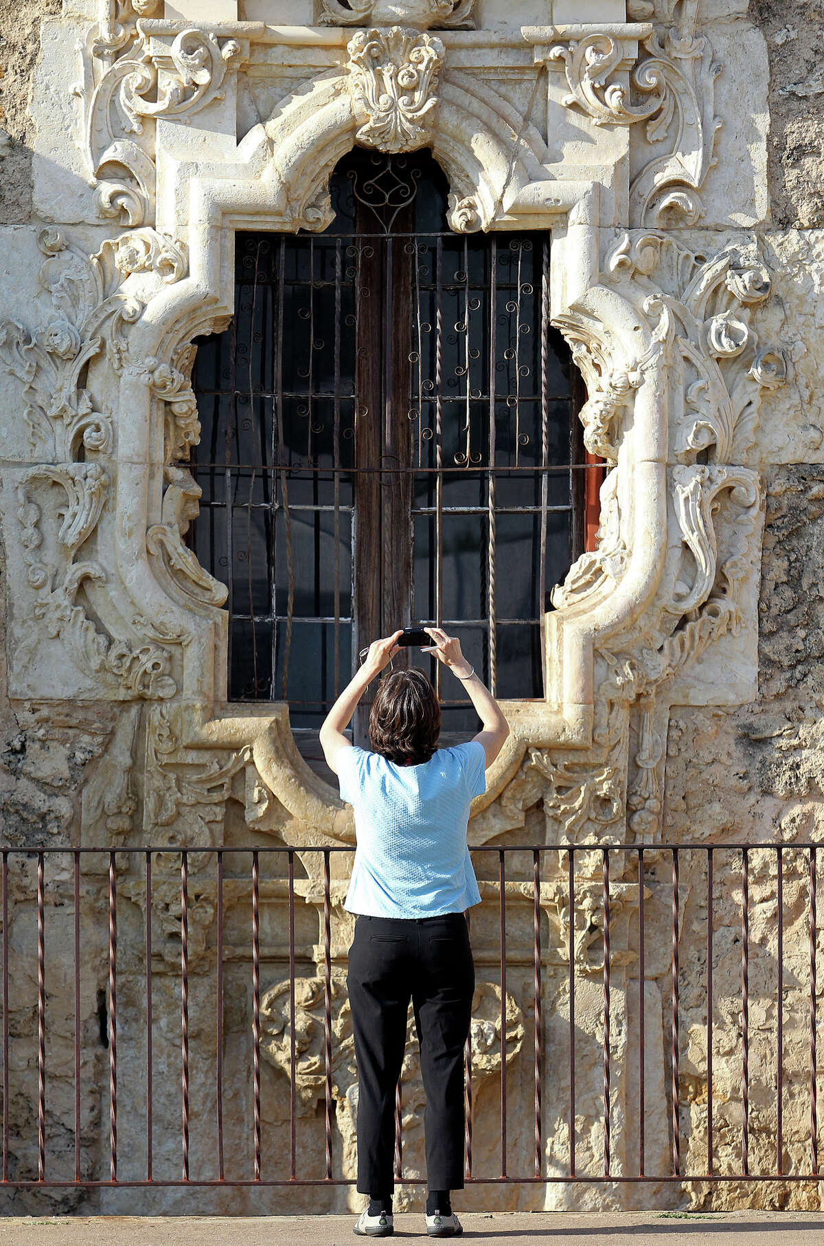 Hannah Blake, with the Erie Canalway National Heritage Corridor from Albany, New York, attempts to recreate a picture she bought on a postcard as a large group of symposium attendees visits the grounds of the San Antonio landmark to consider World Heritage Site nomination on May 31, 2012.