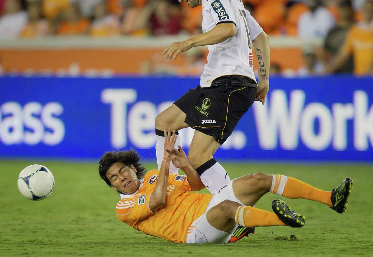 Houston Dynamo midfielder Josuej Soto (18) hits the turf as he loses a challenge to Valencia defender Antonio Barragan (12) during second half of the BBVA Compass Dynamo Charities Cup friendly soccer match on Thursday, May 31, 2012, at BBVA Compass Stadium in Houston. Valencia won the game 2-1.