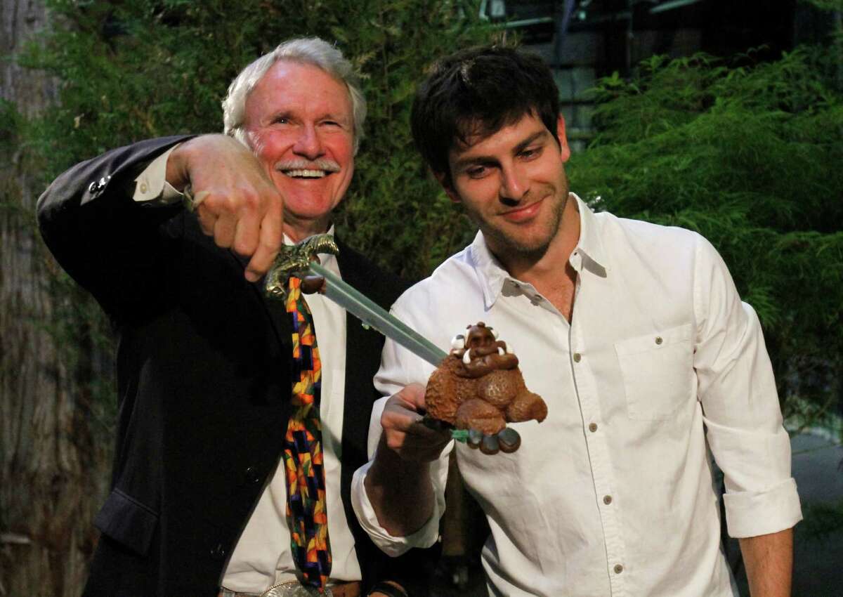 Oregon Gov. John Kitzhaber, left, holds up a piece a cake as Grimm cast member David Giuntoli helps during the kickoff party of second season production for their NBC television series in Portland, Ore., Tuesday, May 29, 2012. Grimm is filmed in Portland.(AP Photo/Don Ryan)