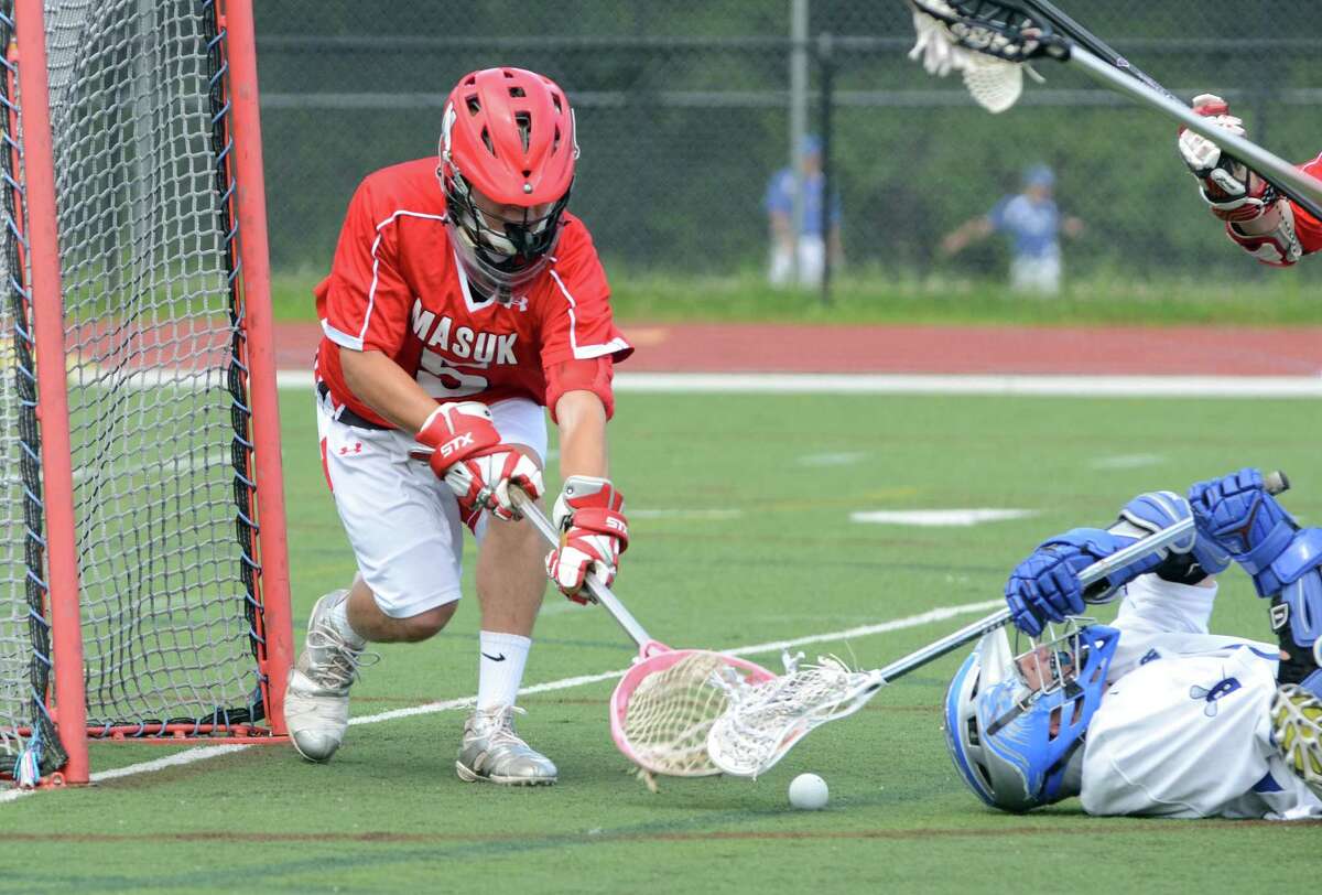Darien's Peter Lindley, on ground, tries to claim a loose ball as Masuk's goalie Kyle Matthews (5) defends during the boys lacrosse Class M quarterfinals at Darien High School on Saturday, June 2, 2012.