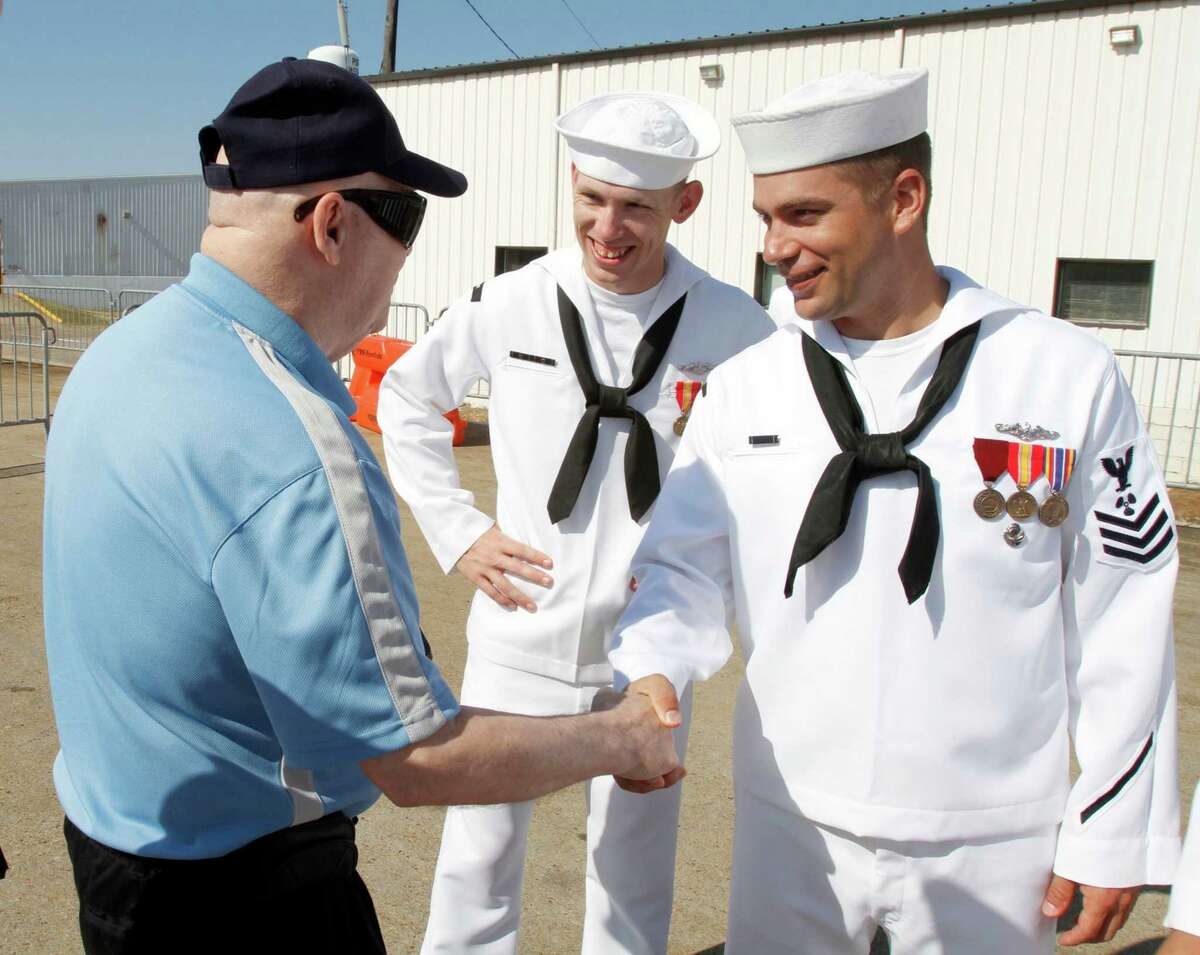Bob Rutherford of the Armed Forces Retirment Home in Gulfport, Mississippi, shakes hands with USS Mississippi crewmen Timothy Sanders and Matt Strickland during commissioning ceremony for the Virginia class submarine on Saturday, June 2, 2012, in Pascagoula, Mississippi.