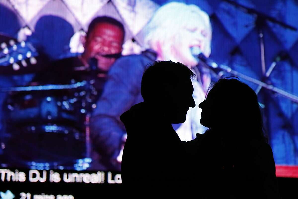 Jeremy Binsdon and Laura Putnam get close to one another in front of a large screen showing Cyndi Lauper's performance simultaneously with live tweets about the Black and White Ball which celebrated the 100th Anniversary of the San Francisco Symphony on Saturday, June 2, 2012. This was the first time the Black and White Ball chose to use tweets as part of their presentation.