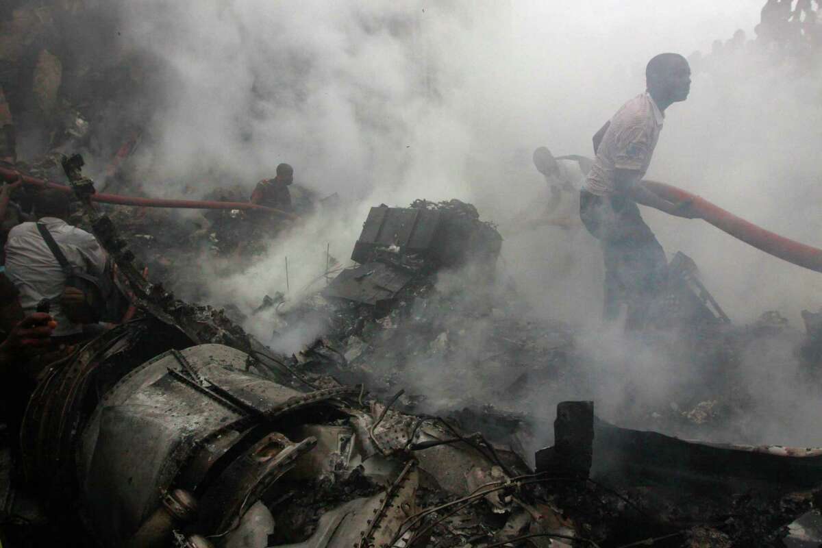 People gather at the site of a plane crash in Lagos, Nigeria, Sunday, June 3, 2012. The passenger plane carrying more than 150 people crashed in Nigeria's largest city on Sunday, government officials said. Firefighters pulled at least one body from a building that was damaged by the crash and searched for survivors as several charred corpses could be seen in the rubble.(AP Photo/Sunday Alamba)
