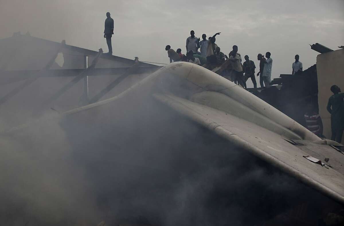 People gather at the site of a plane crash in Lagos, Nigeria, Sunday, June 3, 2012. A commercial airliner crashed into a densely populated neighborhood in Nigeria's largest city on Sunday, killing all 153 people on board and others on the ground in the worst air disaster in nearly two decades for the troubled nation. (AP Photo/Sunday Alamba)