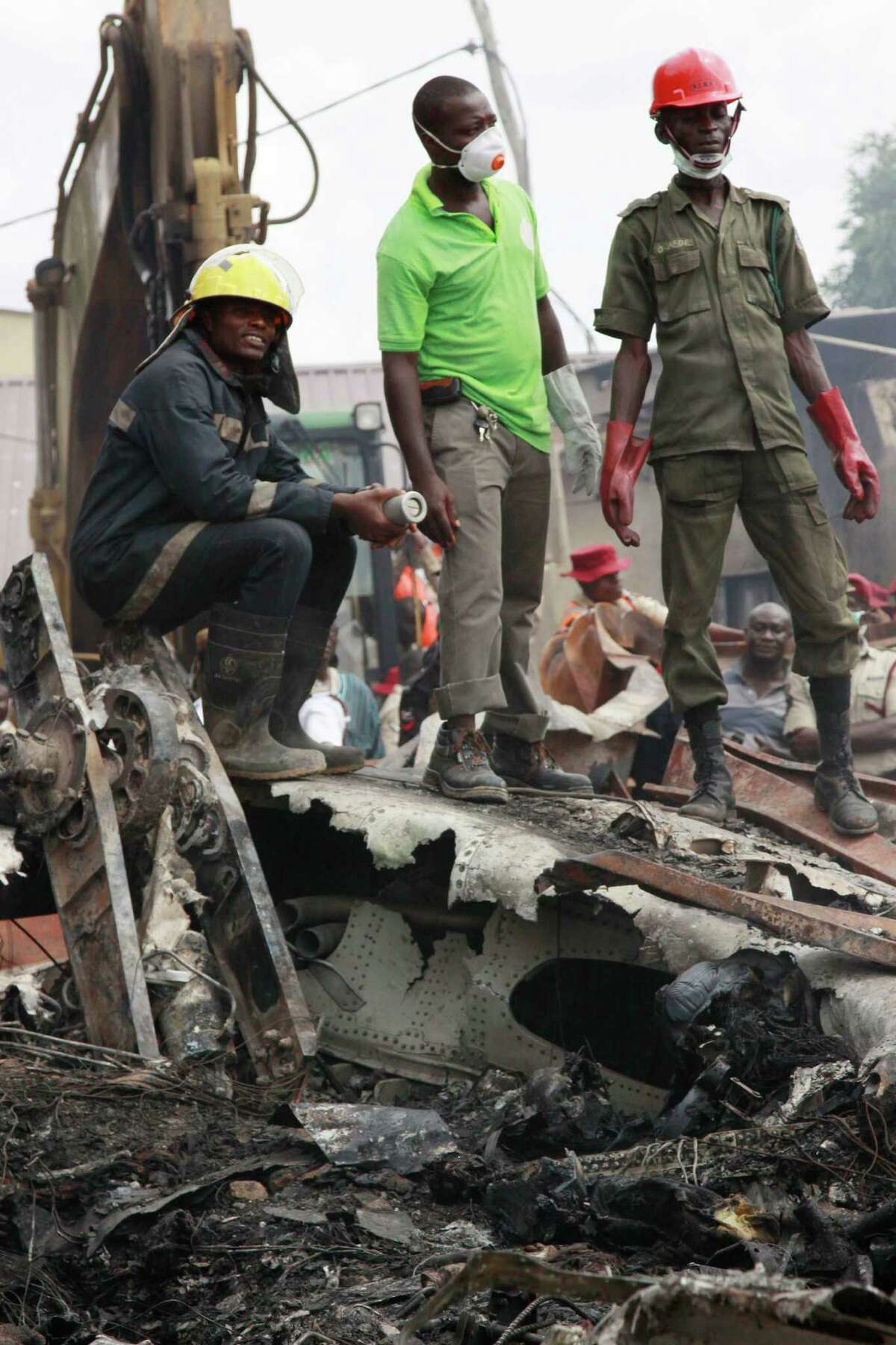 Rescue workers take a break at the site of a plane crash in Lagos, Nigeria, Monday, June 4, 2012. A passenger plane carrying more than 150 people crashed in Nigeria's largest city on Sunday, government officials said. Firefighters pulled at least one body from a building that was damaged by the crash and searched for survivors as several charred corpses could be seen in the rubble.(AP Photo/Sunday Alamba)