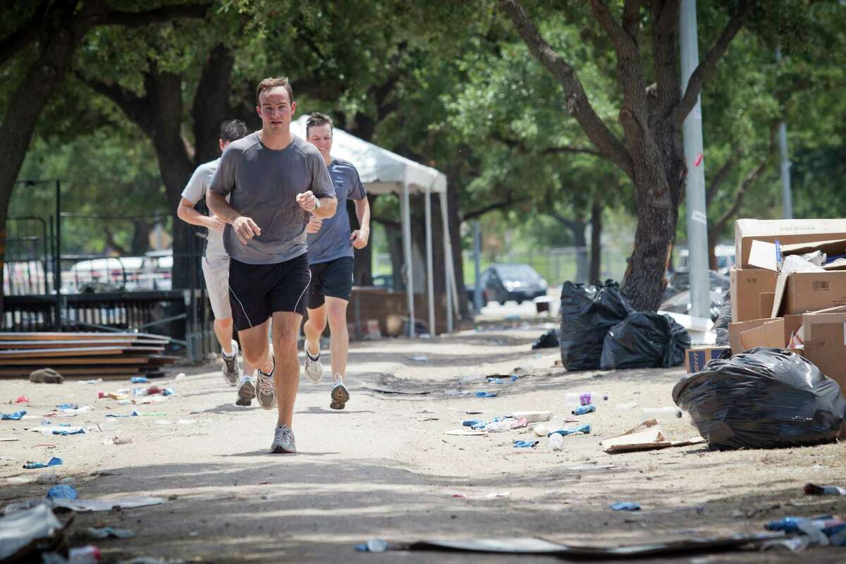 Jon Davis runs along Allen Parkway as crews work Monday noon June 4, 2012, to clean up Eleanor Tinsley Park along Buffalo Bayou following the weekend's 4th annual Free Press Summer Fest. Willie Nelson and Snoop Dog headlined the two day concert event. "It's horrible, it's discusting," Davis said of the piles of trash that lined the running path between the park and Allen Parkway. Nathan Lindstrom/Special to the Chronicle ©2012 Nathan Lindstrom