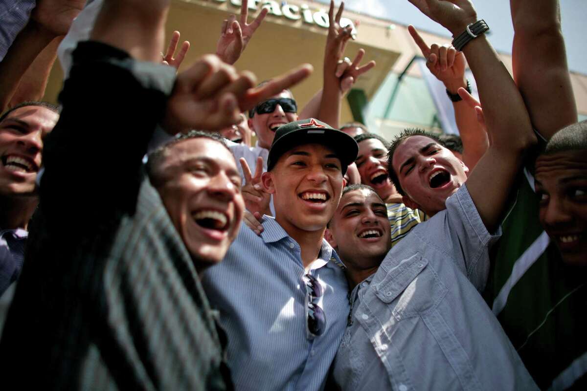 Student and baseball player Carlos Correa, center, is surrounded by classmates upon his arrival to the Puerto Rico Baseball Academy High School in Caguas, Puerto Rico, Tuesday, June 5, 2012. Correa, the 17-year-old slugging shortstop made hometown history on Monday after being selected by the Houston Astros as No. 1 in the Major League Baseball draft, becoming the first No. 1 overall pick from Puerto Rico. (AP Photo/Ricardo Arduengo)