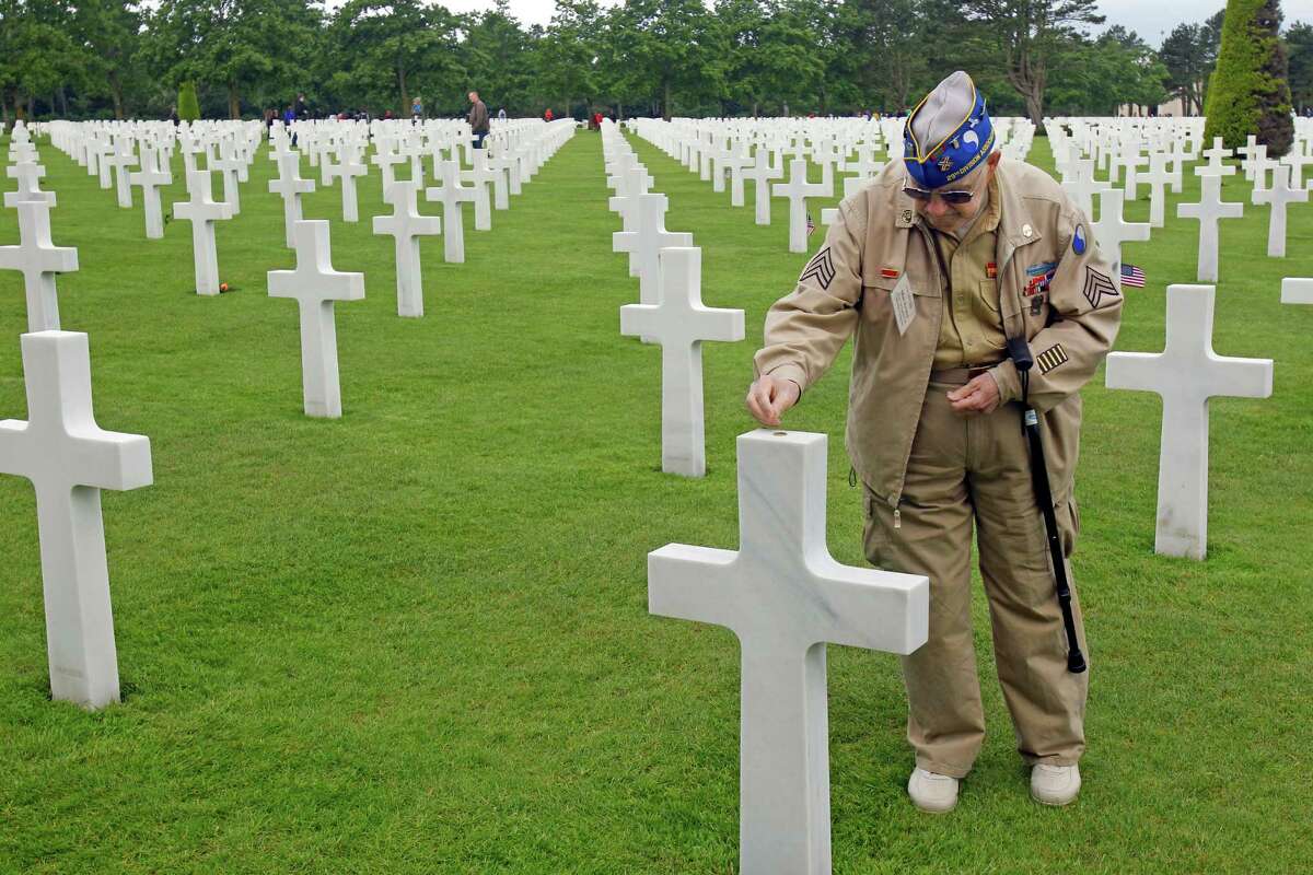 U.S. WW II veteran Clarence Mac Evans, 87, from West Virginia, who landed in Normandy on June 6, 1944, with the 29th infantery division, puts a coin on the tomb of fellow Franck Nuzzo, from the 29th division who died on June 6, 1944, at the Colleville American military cemetery.(AP Photo/Remy de la Mauviniere)