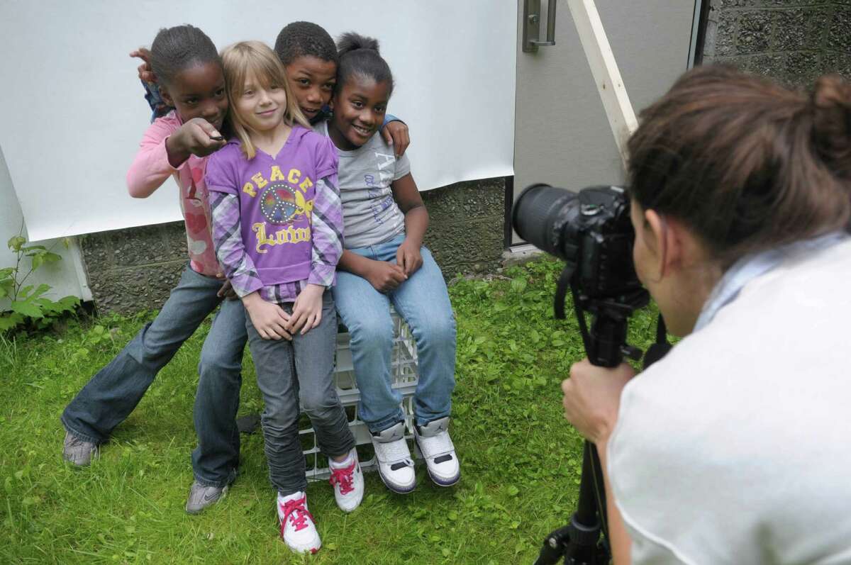 Sasha Sicurella, right, adjusts her camera as second graders, from left, Zhamaije Monroe, Destiny Perlmutter, Kygii Humes and Mavihaa Chandler pose together at Arbor Hill Elementary School on Wednesday, June 6, 2012 in Albany, NY. Sasha Sicurella, an artist and photographer was at the school helping children take self portraits as part of her on-going international project. The children sit in front of a backdrop and then trigger the camera with a handheld remote. (Paul Buckowski / Times Union)