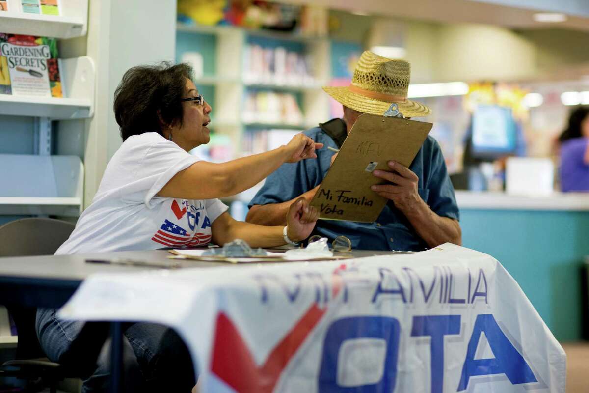 Linda Vargas, a volunteer with Mi Familia Vota, a national group that helps Latinos become citizens and register to vote, assists Harvey Stroh with registration papers last month in Denver.