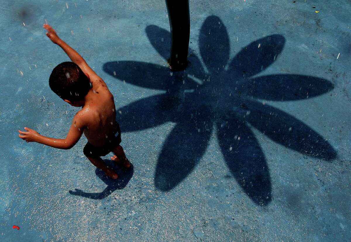 In the shadow of a flower-shaped water feature, Jonas Alejandro, 4, plays in a splash pad at Settegast Park east of downtown Monday, June 11, 2012, in Houston.