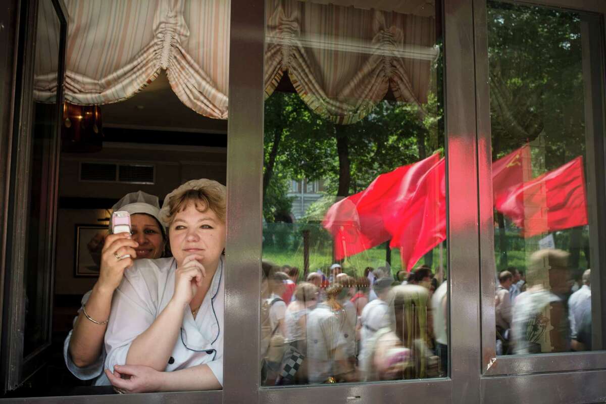 A woman takes a picture of protesters marching by during a demonstration in Moscow, June 12, 2012.