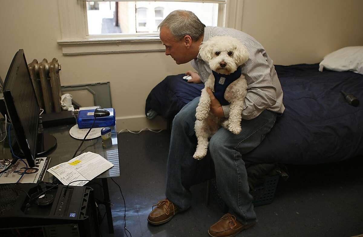 Matt Traywick with his dog Charlie as he checks the internet in his Tenderloin home in San Francisco, California, on Tuesday, June 12, 2012.