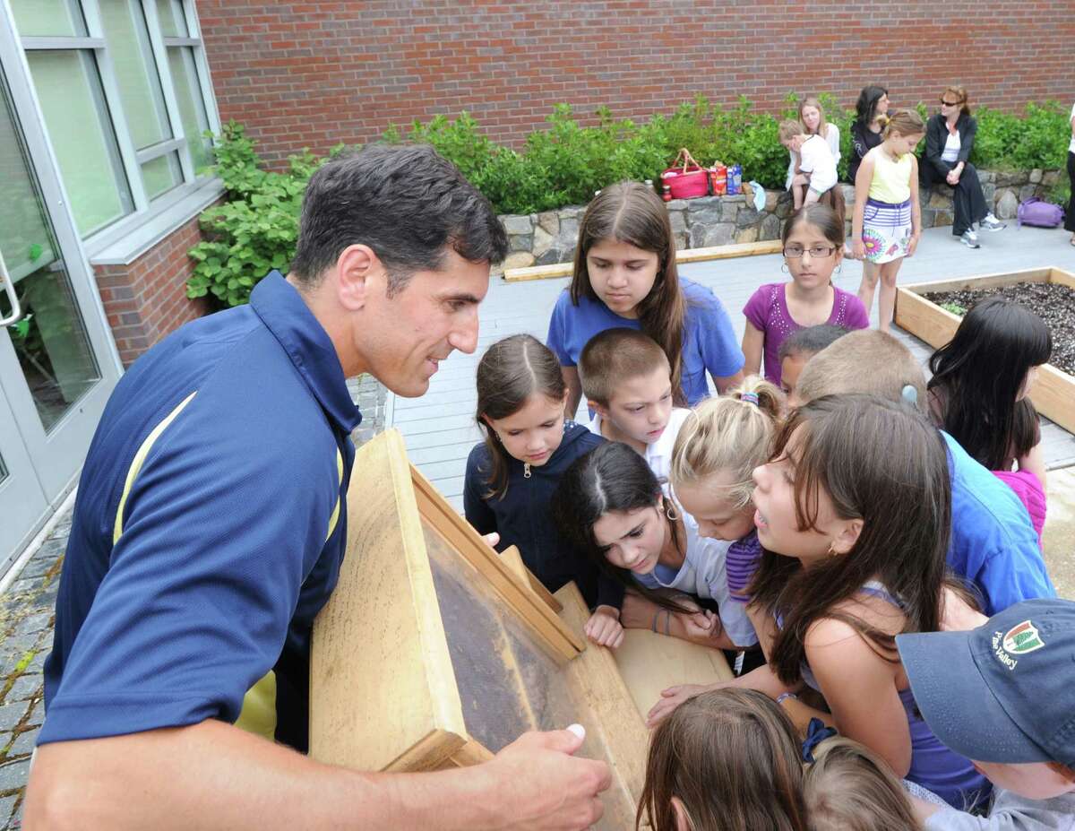 At left, Carl Marinaccio of Greenwich, displays a hive of Italian honey bees to students in the organic vegetable garden at Glenville School, Wednesday, June 13, 2012. Marinaccio, a bee expert, gave an educational talk about the bees and their place in the ecosystem to the students.