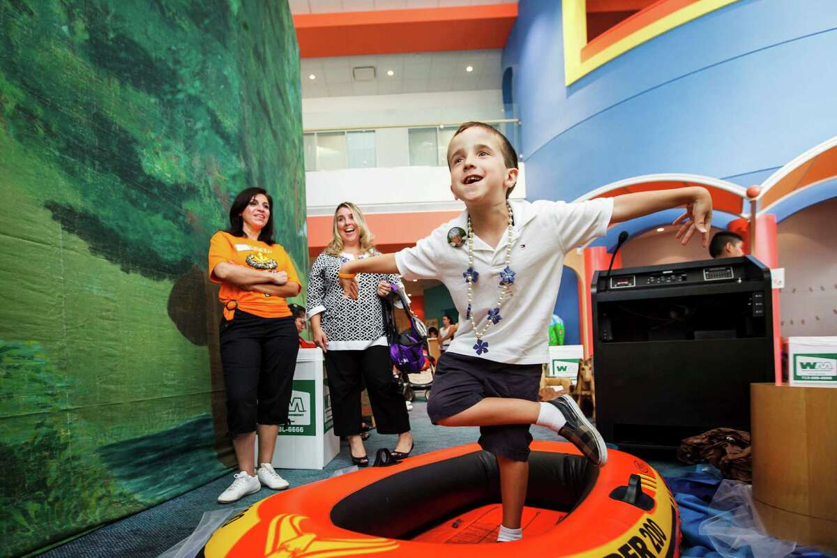 Peter Tsatsaronis, 9, plays a Kinect rafting game in a real raft as Amalia Gatlegos, left, and Michelle Tsatsaronis, center, look on at the Camp Periwinkle Day at Texas Children's Cancer Center, Wednesday, June 13, 2012, in Houston. The Periwinkle Foundation, with the support of BG Group, is bringing a day of fun activities to the outpatient and inpatient children and young adults under care at Texas Children's Cancer Center.