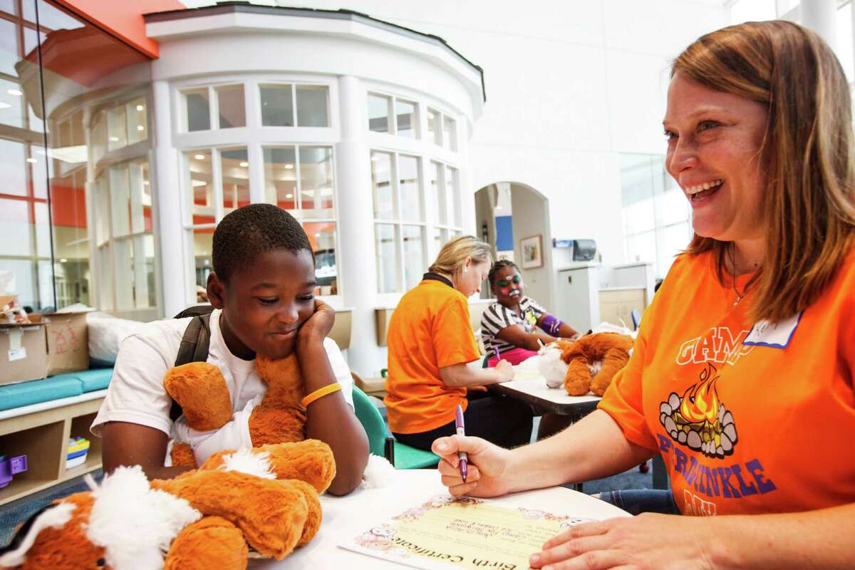 Cameron Taylor, 9, left, gets help filling out the birth certificate for his newly stuffed fox during the Build-A-Buddy activity with the help of Kelly Sowa, right, at the Camp Periwinkle Day at Texas Children's Cancer Center, Wednesday, June 13, 2012, in Houston.