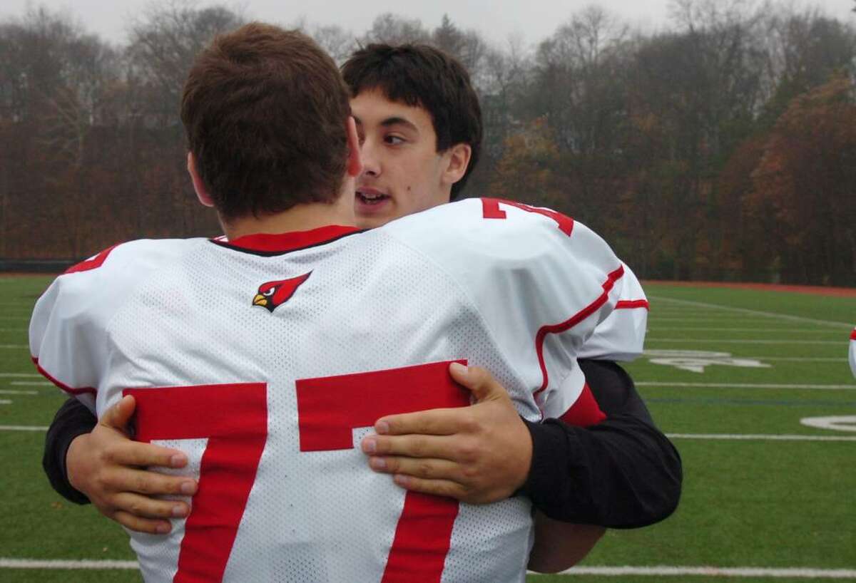 Greenwich High School football captain Mike Lefflbine hugs teammate Anthony Schepis as the annual burning of the shoes ceremony wraps up. The ceremony is symbolic of how no one can ever fill the shoes of the graduating seniors.