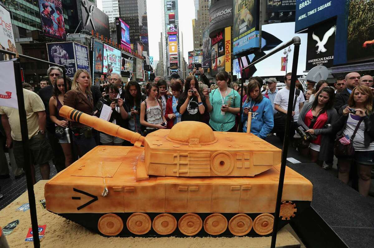 NEW YORK, NY - JUNE 14: Tourists photograph a 500 pound cake in the shape of a tank after watching a ceremony marking the U.S. Army's 237th anniversary on June 14, 2012 in Times Square in New York City. U.S. Army Chief of Staff Gen. Raymond Odierno cut the cake before swearing in16 new recruits during the event. ''Cake Boss'' reality show Buddy Valastro helped Odierno cut the cake, which Valastro said took eight of his staff three days to prepare for the event.