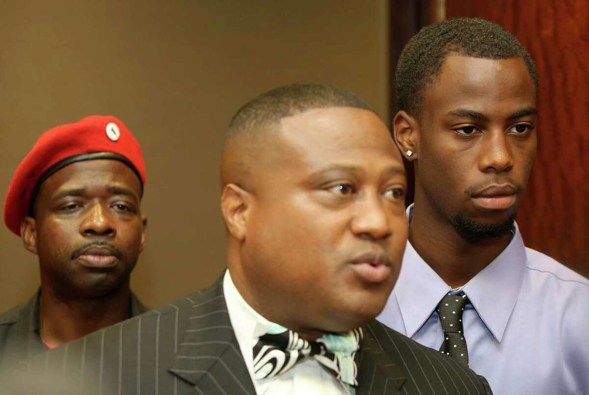 Chad Holley listens as Quanell X speaks to the media after Holley appeared in court Friday morning regarding his arrest on a burglary charge on Wednesday.