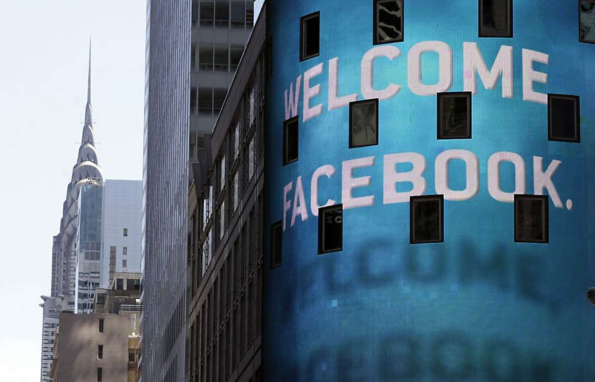 The Chrysler Building is visible behind the animated facade of the Nasdaq MarketSite, welcoming the Facebook IPO, in New York's Times Square, Friday, May 18, 2012. Facebook's stock is trading up Friday, as investors seek to put a dollar value on the company that turned online social networking into a global cultural phenomenon. (AP Photo/Richard Drew)